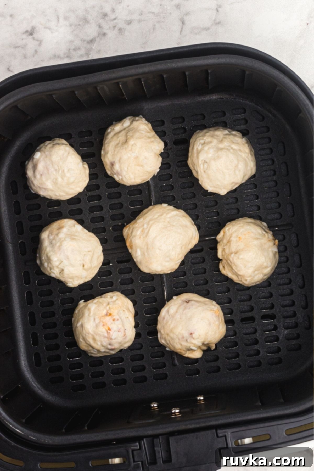 Air Fryer Pizza Poppers 6 Biscuits filled with pizza toppings, wrapped into balls placed in the air fryer basket