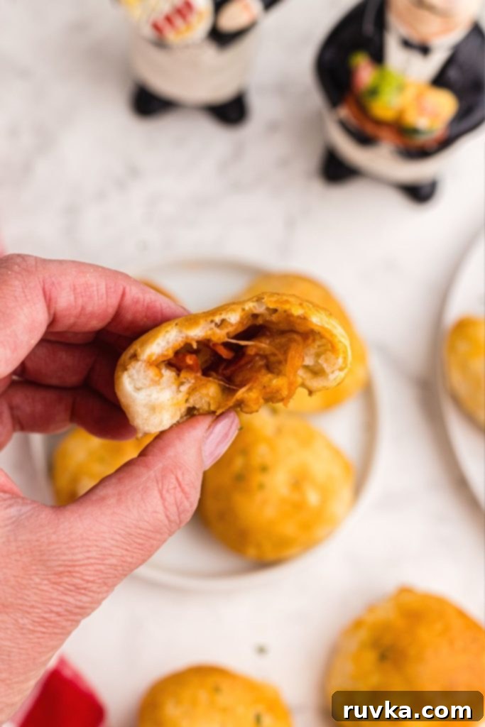 Air Fryer Pizza Poppers 8 Close up photo of hand holding half of pizza bomb, showing melted cheese, sauce, and pepperoni