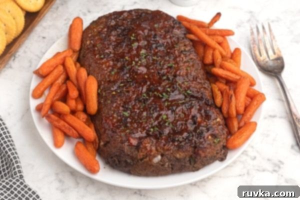 Easy Air Fryer Copycat Cracker Barrel Meatloaf 2 Air Fryer Meatloaf on a white plate with baby carrots around the meatloaf.