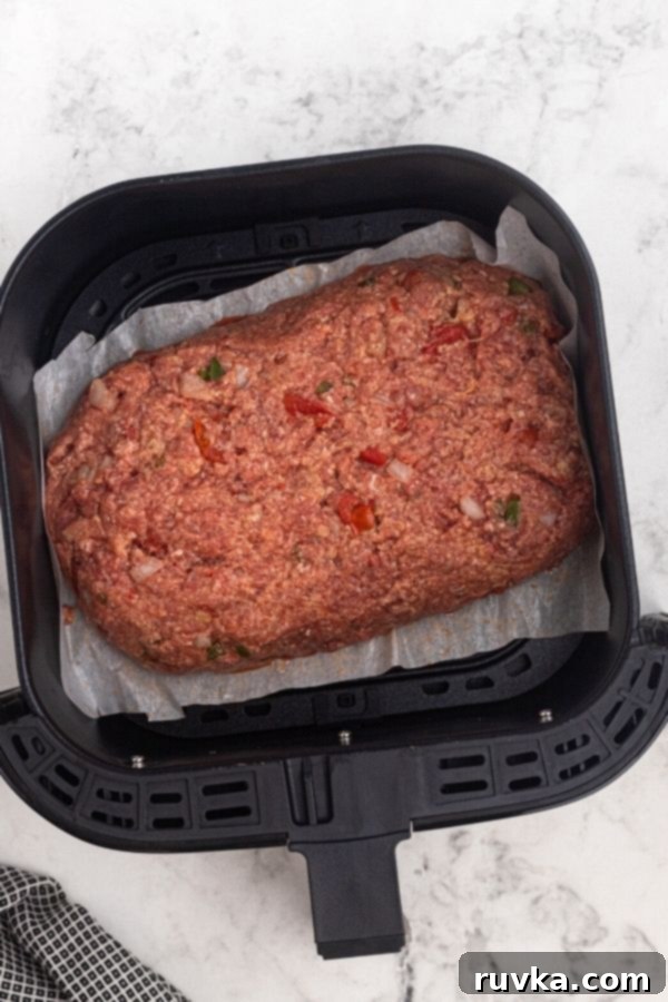 Easy Air Fryer Copycat Cracker Barrel Meatloaf 4 Uncooked meatloaf in the air fryer basket.