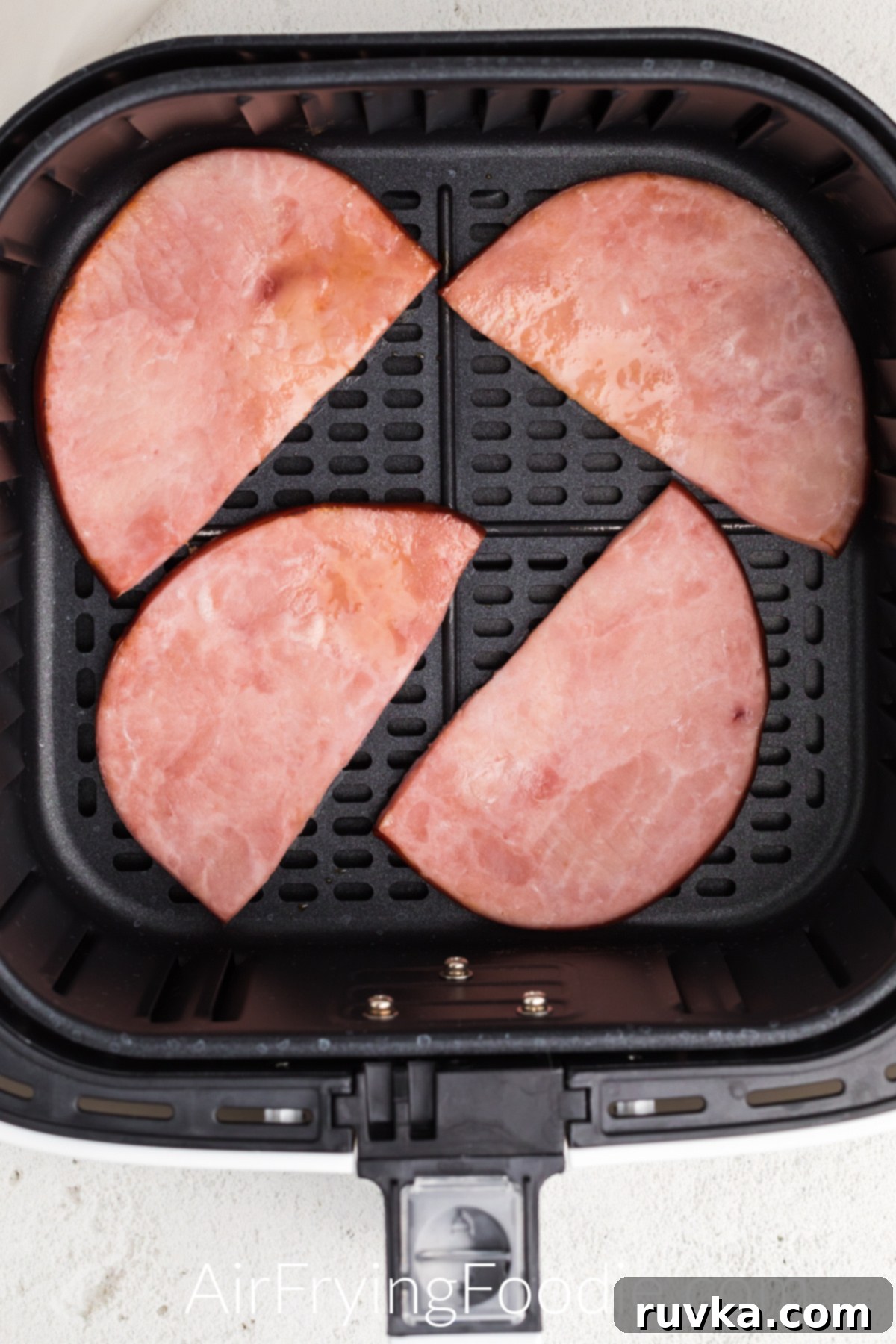 Easy Air Fryer Ham Steak 2 Ham steaks in air fryer basket, ready to remove and serve.