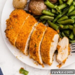 Perfectly Crispy Air Fryer Shake and Bake Chicken 9 Golden crispy chicken sliced and served on a white plate with vegetables and a fork