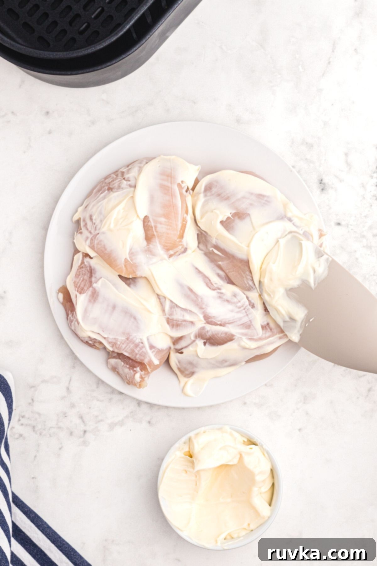 Perfectly Crispy Air Fryer Shake and Bake Chicken 4 Chicken breast on a white plate being coated with mayonnaise