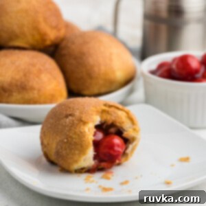 Air Fryer Cherry Pie Bites 10 Air Fryer Cherry Pie Bomb with a bite taken out of it on a white plate.