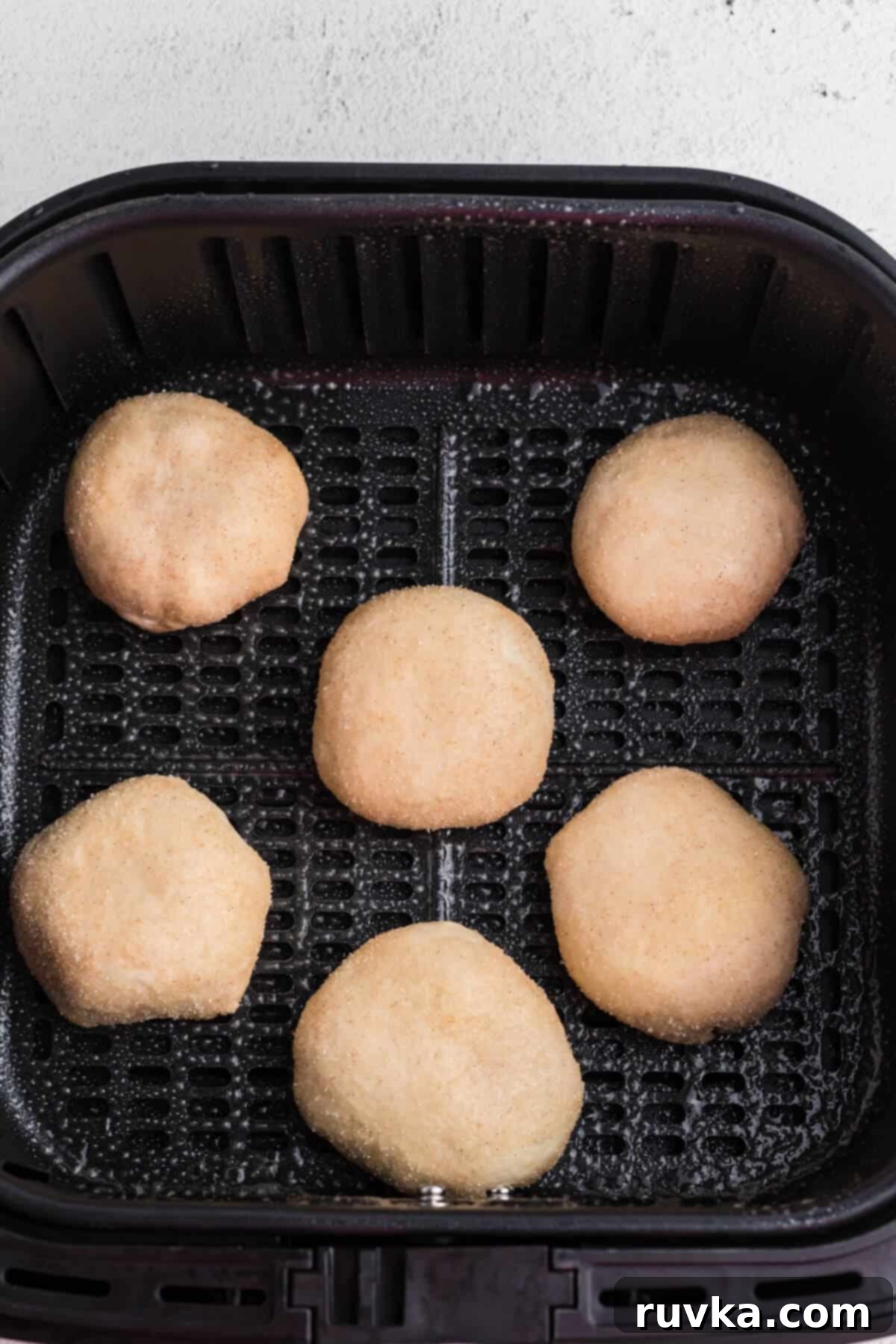 Air Fryer Cherry Pie Bites 7 biscuit dough placed into the basket of the air fryer and the tops have been sprayed with oil. ready to cook.