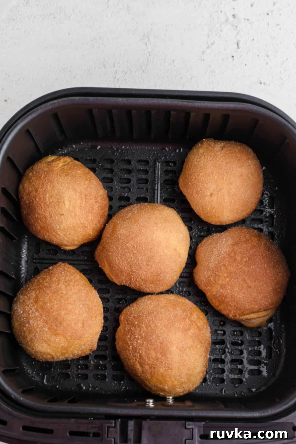 Air Fryer Cherry Pie Bites 8 golden brown cherry pie bombs in the basket of the air fryer.