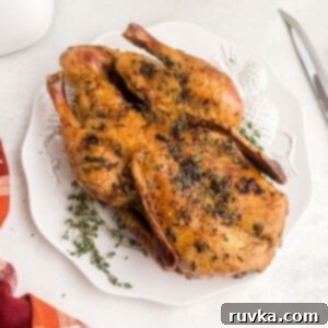 Effortless Easter with Your Air Fryer 13 Whole golden duck on a white platter with a sprig of thyme