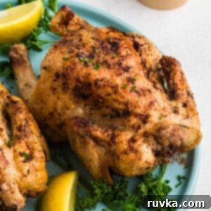 Effortless Easter with Your Air Fryer 14 Golden brown crispy Cornish hens on a light blue plate with lemon wedges and parsley garnish.
