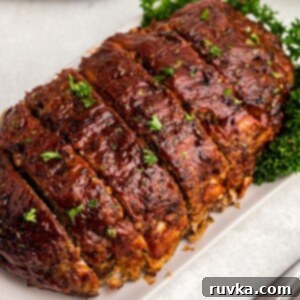 Effortless Easter with Your Air Fryer 16 Juicy meatloaf sliced on a white plate sprinkled with parsley flakes
