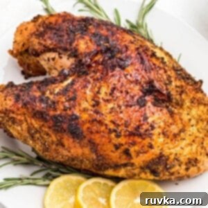 Effortless Easter with Your Air Fryer 5 Golden brown seasoned turkey breast on a white plate with lemon slices for garnish.