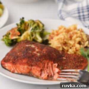 Effortless Easter with Your Air Fryer 8 Flaky seasoned salmon on a white plate with rice and broccoli with a fork bite