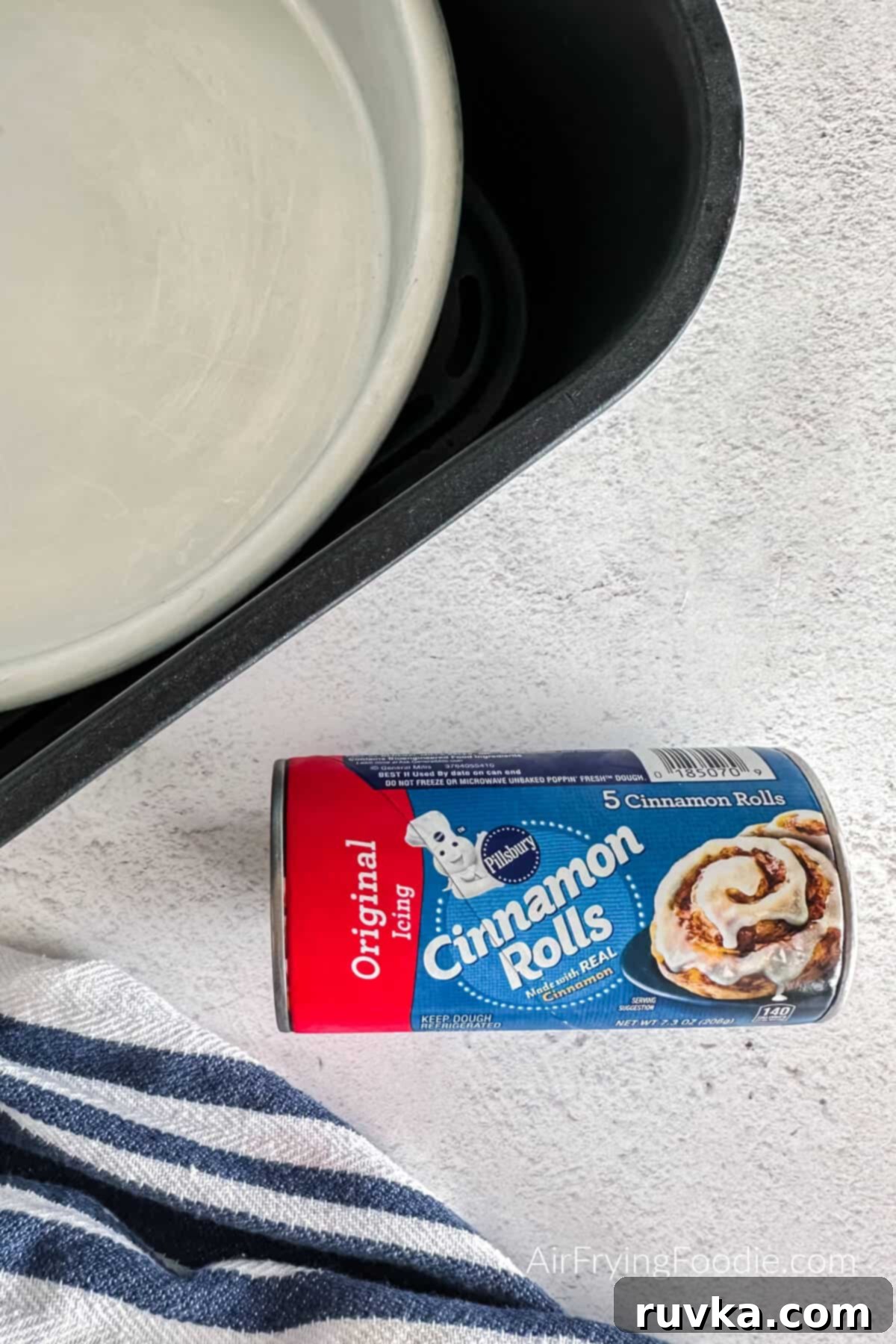 Air-Fried Cinnamon Rolls 3 Can of Pillsbury cinnamon rolls next to an air fryer, ready to be prepared.
