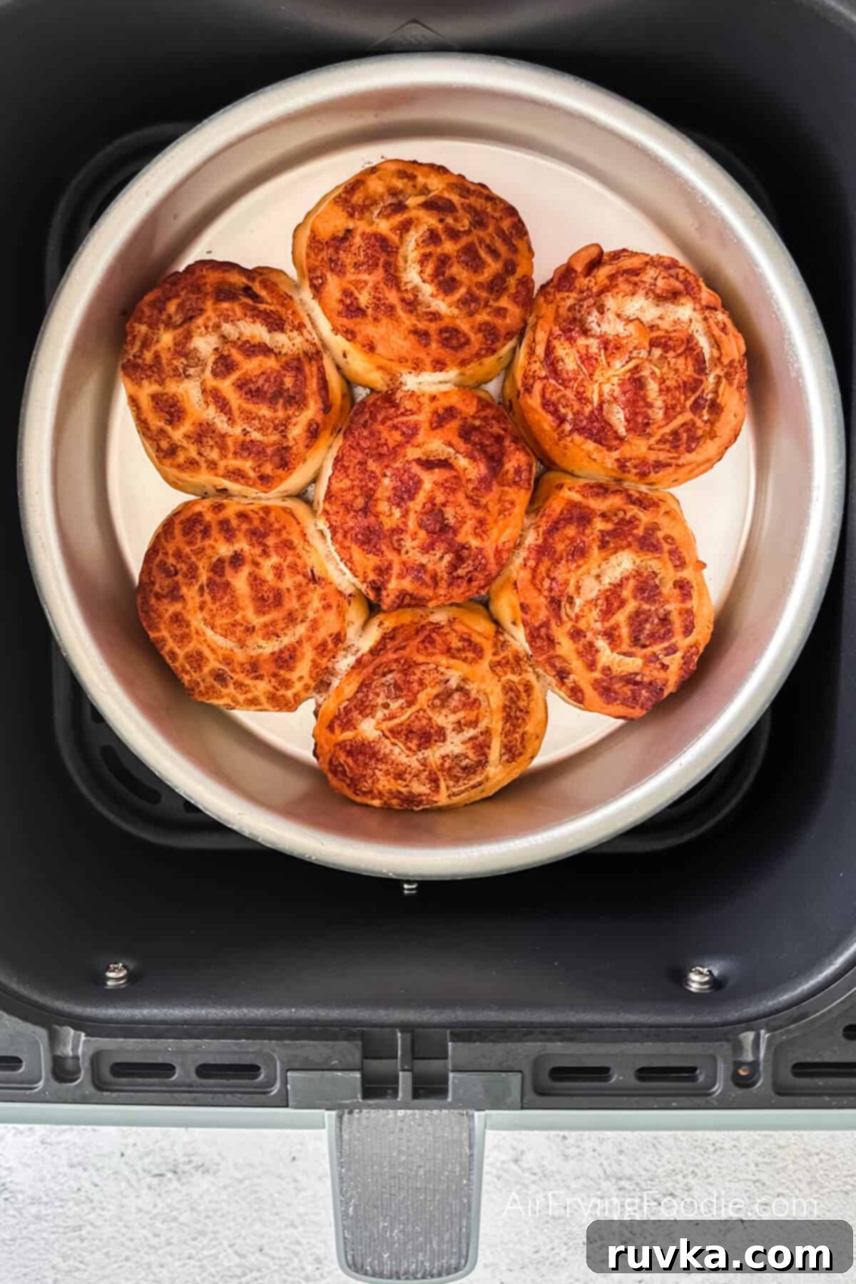 Air-Fried Cinnamon Rolls 5 Fully cooked, golden brown cinnamon rolls in the pan, still in the air fryer basket.