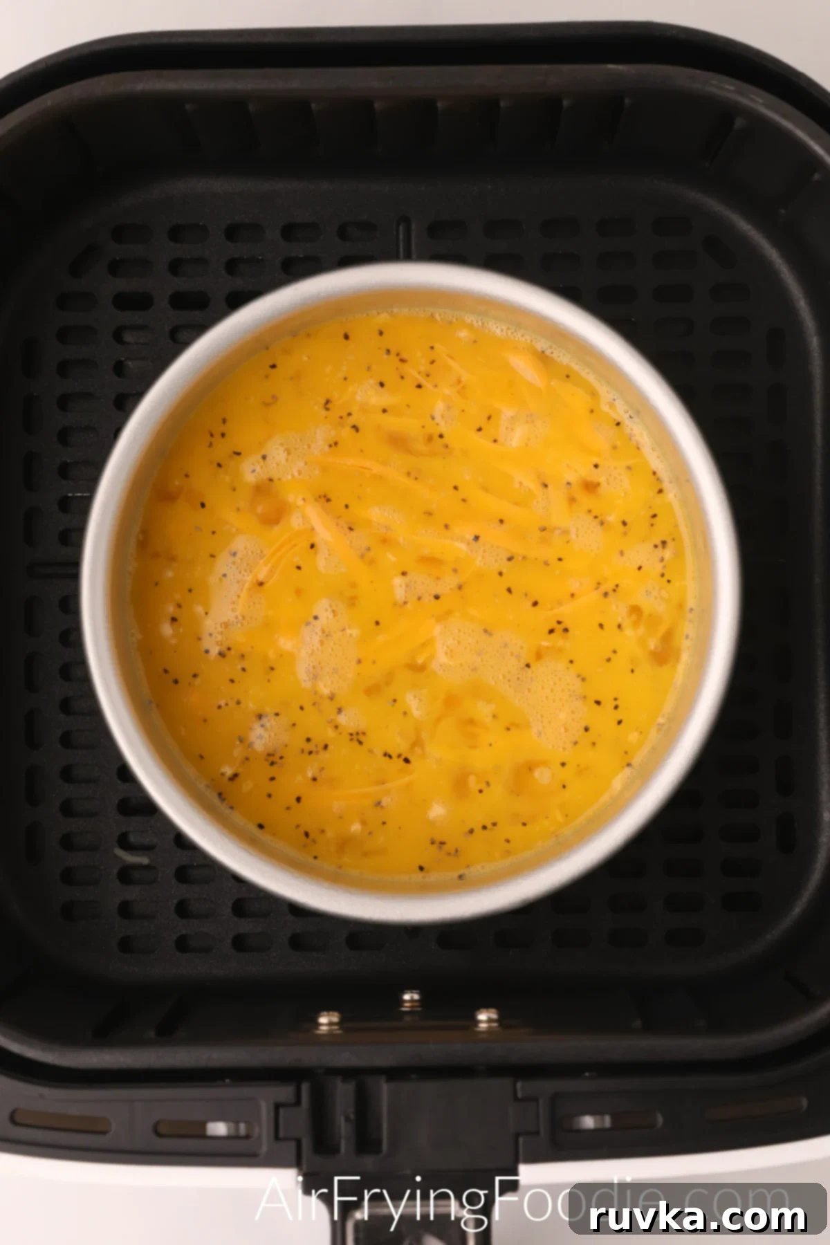 Fluffy Air Fryer Scrambled Eggs 5 Whisked eggs and cheese in a bowl in the basket of the air fryer.