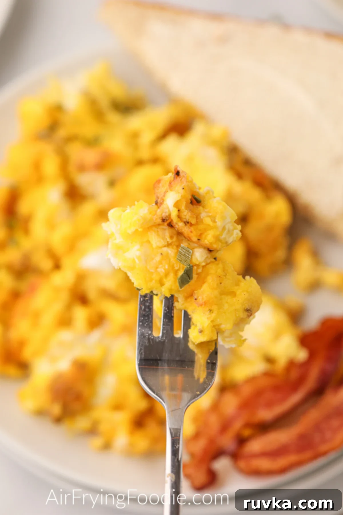Fluffy Air Fryer Scrambled Eggs 10 Scrambled eggs on a fork ready to eat.