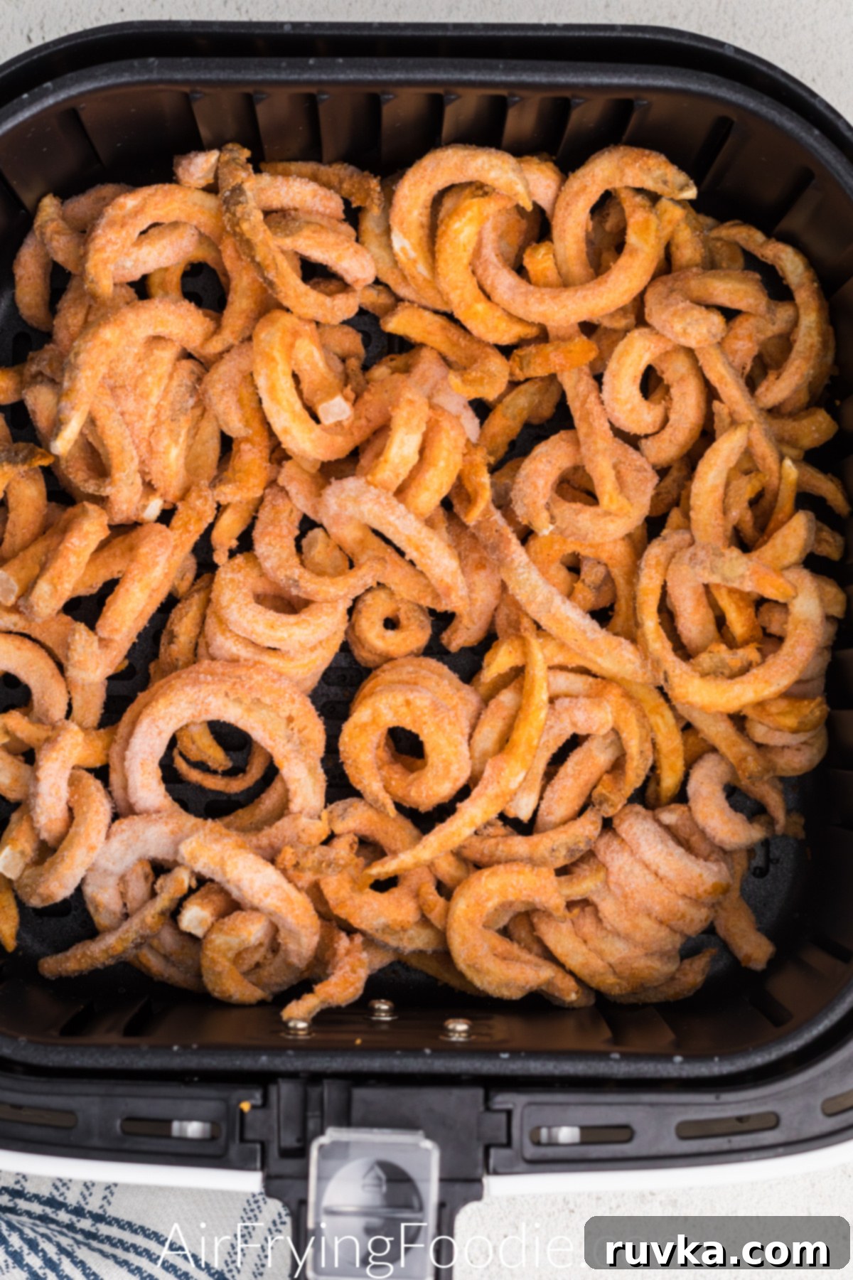 Crispy Air Fryer Frozen Curly Fries 4 frozen curly fries in air fryer basket.