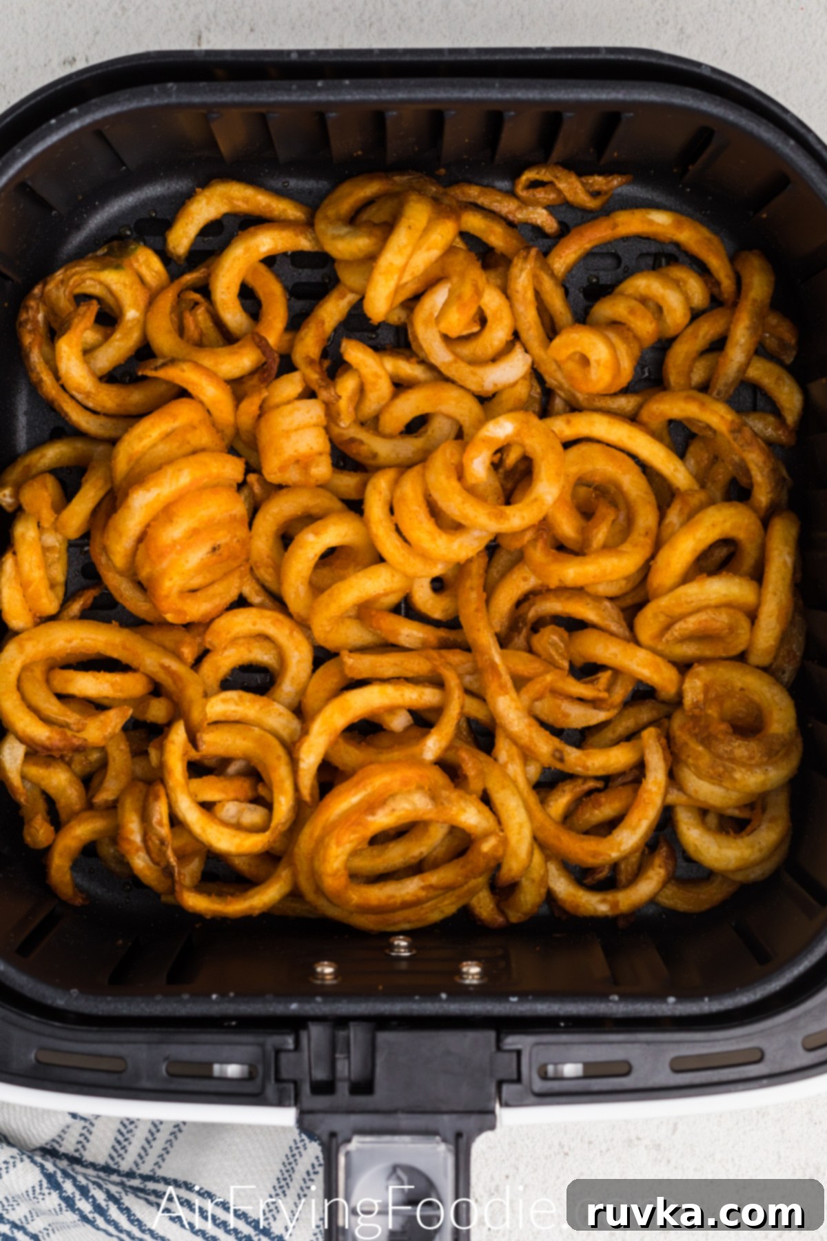Crispy Air Fryer Frozen Curly Fries 5 Cooked and crispy curly fries in air fryer basket, ready to serve.