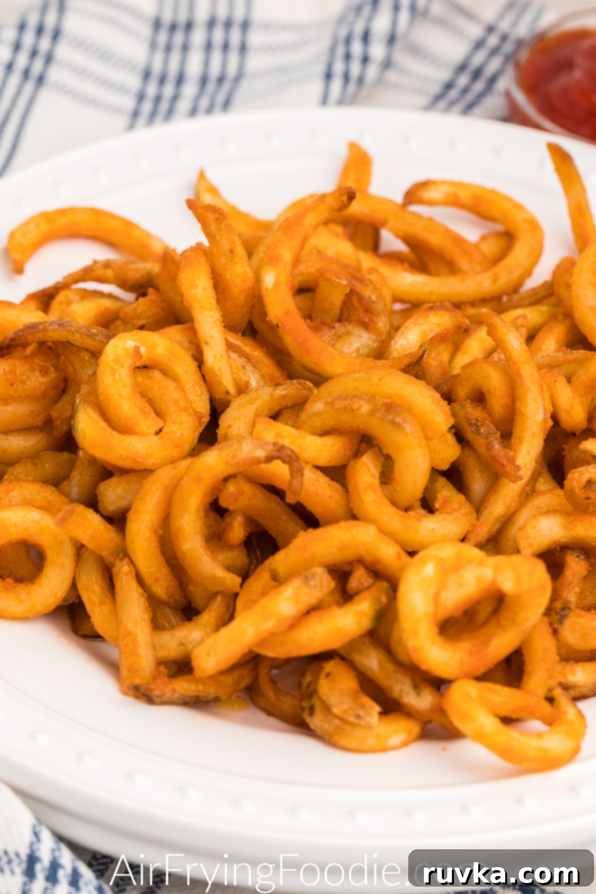 Crispy Air Fryer Frozen Curly Fries 6 Close up of curly fries on a white plate that were made in the air fryer.
