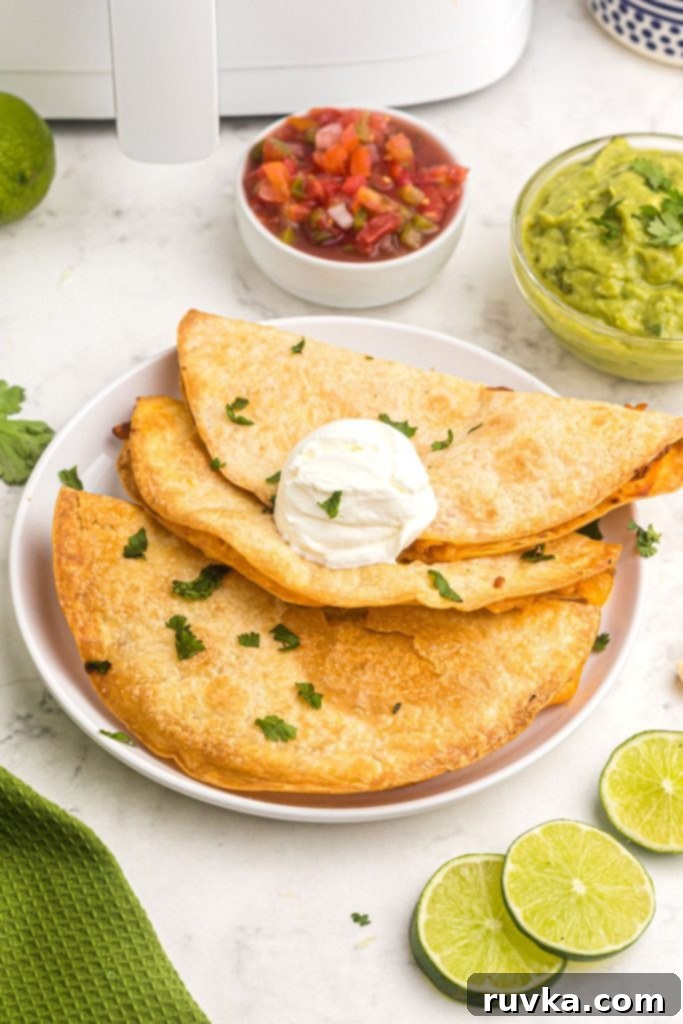 Crispy Air Fryer Quesadillas 2 Crispy air-fried cheese quesadillas served on a white plate with fresh guacamole and vibrant salsa