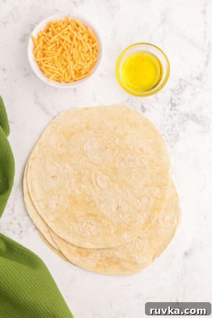 Crispy Air Fryer Quesadillas 3 Selection of key ingredients including flour tortillas, shredded cheese, and olive oil, arranged on a surface, ready for making air fryer quesadillas.