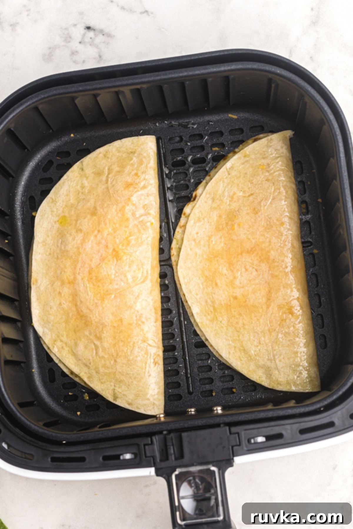 Crispy Air Fryer Quesadillas 6 Uncooked tortillas, perfectly folded in half and generously filled with cheese, carefully arranged in the air fryer basket, awaiting cooking.