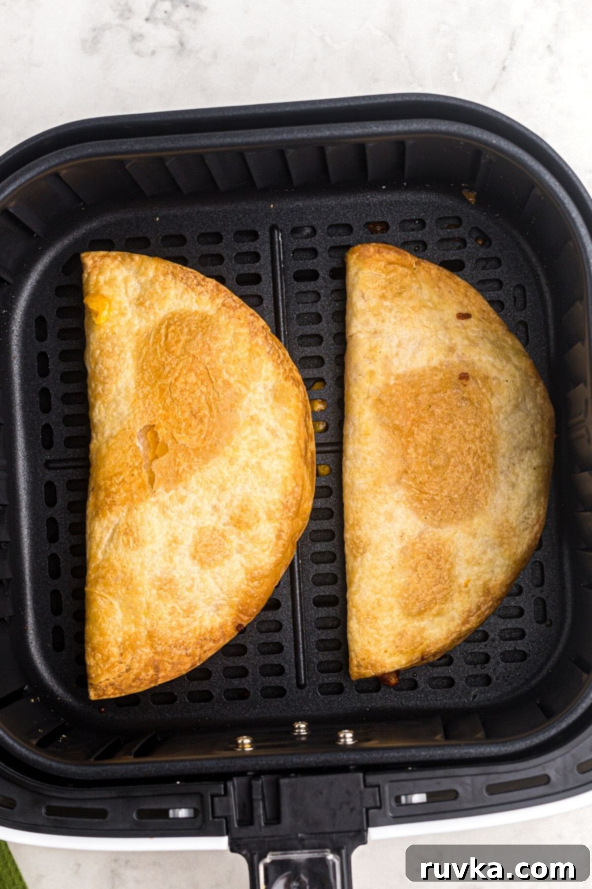 Crispy Air Fryer Quesadillas 7 Crispy golden quesadillas, freshly cooked to perfection and still in the air fryer basket, radiating warmth and ready to be removed.