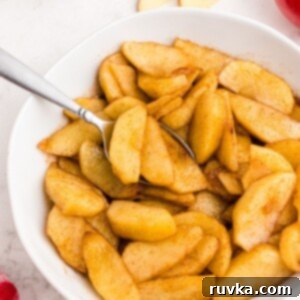 Perfect Air Fryer Apples 8 Golden juicy sliced apples in a white bowl being scooped with a spoon
