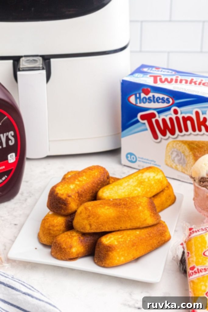 Warm Golden Air Fryer Twinkies 3 Two perfectly golden crispy Air Fryer Twinkies resting on a white plate, with a modern air fryer visible in the soft background.