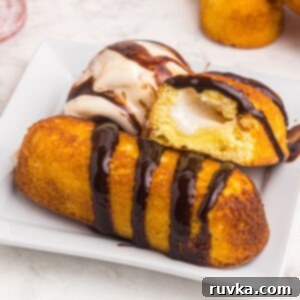 Warm Golden Air Fryer Twinkies 9 Golden crispy Air Fryer Twinkie on a white plate, served with a scoop of ice cream and drizzled with chocolate sauce, ready to be enjoyed.