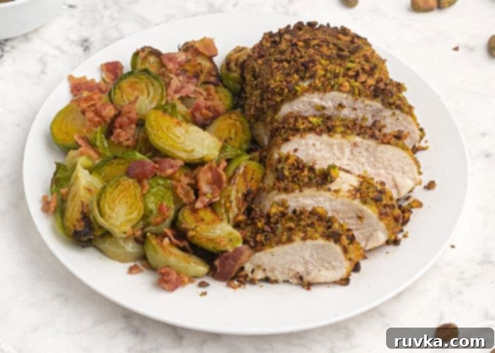Crispy Pistachio Air Fryer Chicken 8 Pistachio crusted chicken on a white plate. sliced and served with brussel sprouts.