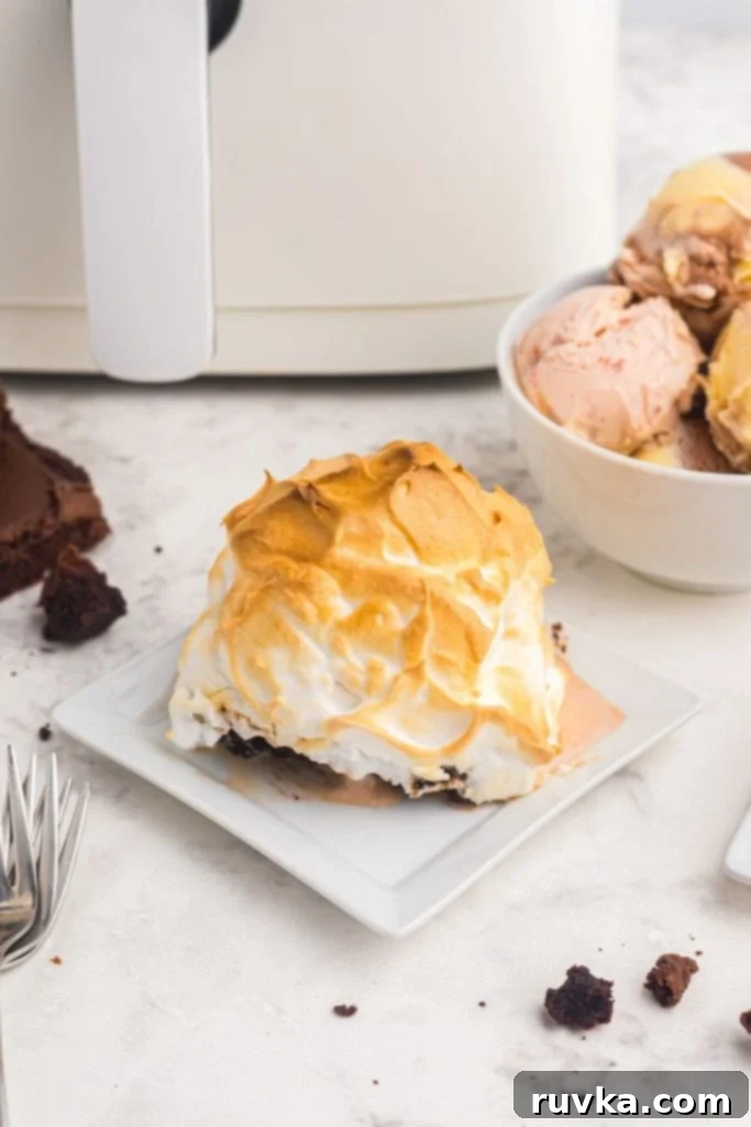 Decadent Air Fryer Brownie Baked Alaska 9 Golden meringue coating over brownie covered with ice cream on a white marble table