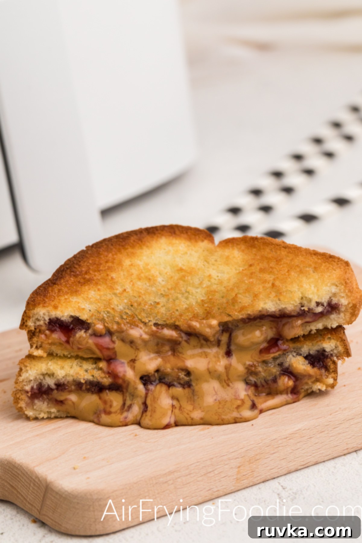 Crispy Air-Fried Peanut Butter and Jelly 2 Air fried peanut butter and jelly sandwich on a cutting board, ready to eat, showing a golden brown crust and a peek of melted filling.