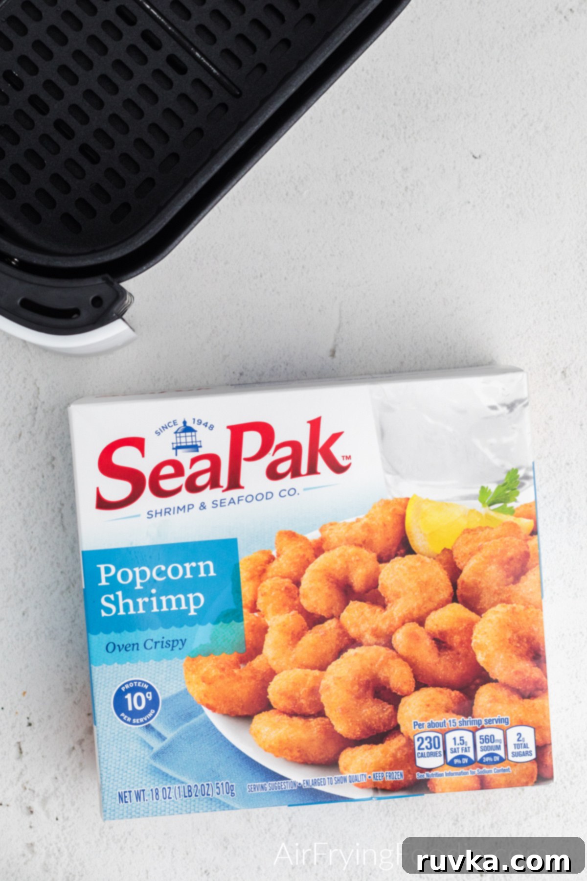 Crispy Frozen Popcorn Shrimp in Air Fryer 4 Seapak frozen popcorn shrimp and the basket of the air fryer on a white table.