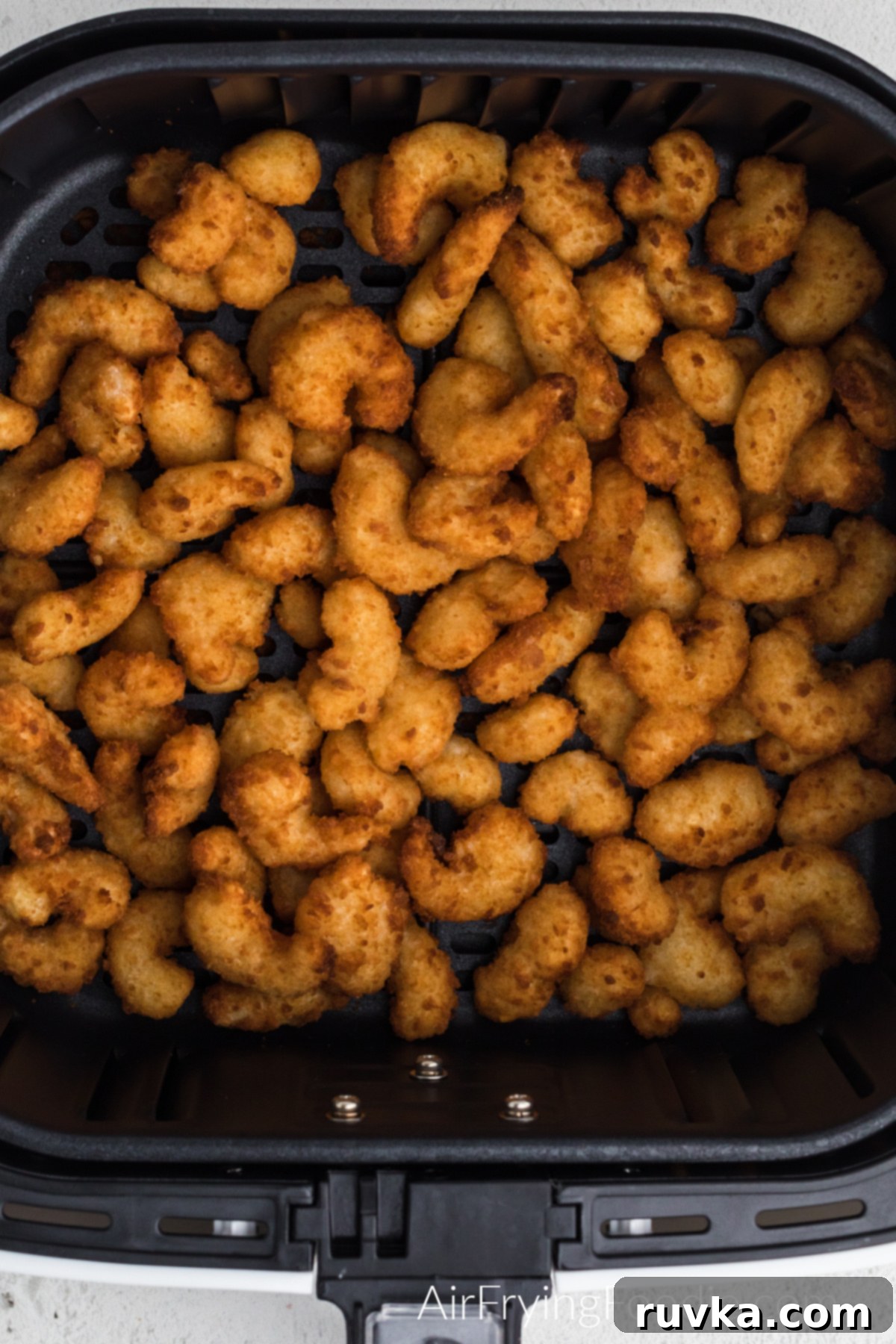 Crispy Frozen Popcorn Shrimp in Air Fryer 6 Crispy golden brown popcorn shrimp in the basket of the air fryer.