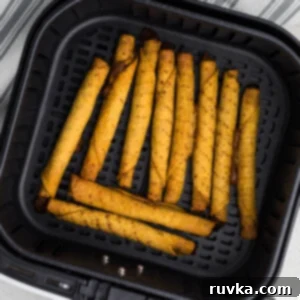 Air Fryer Fiesta Mexican Delights 7 fully cooked taquitos in the air fryer basket in a single layer, ready to be removed and served.