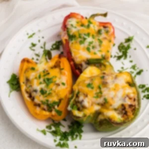 Air Fryer Fiesta Mexican Delights 9 Stuffed Peppers made in the air fryer and topped with cheese and parsley and served on a white plate.