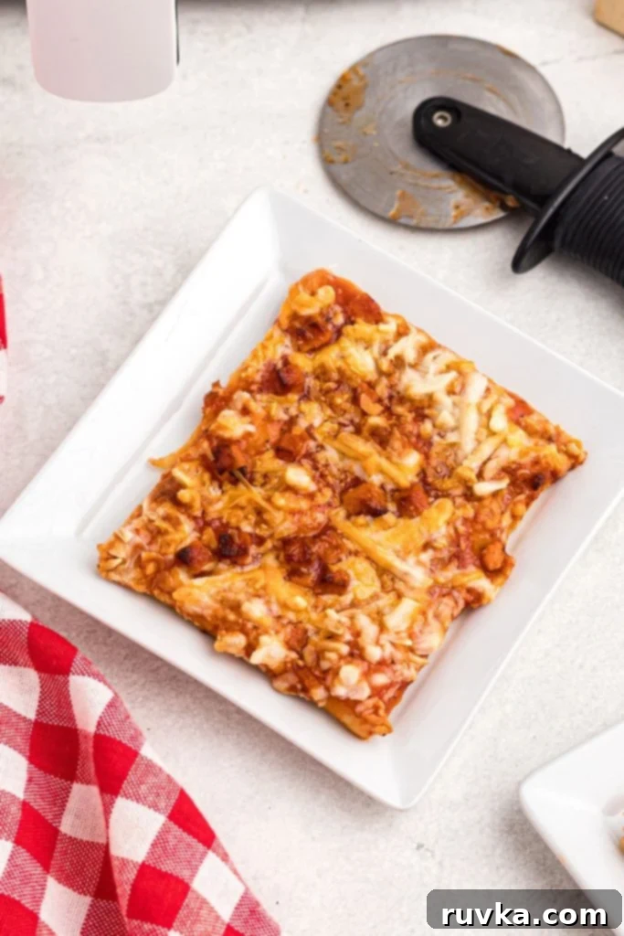 Crispy Air Fryer Tostino's Pizza 7 Golden slice of pizza on a small white square plate with red and white checked cloth