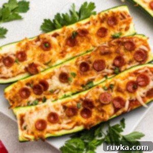 Quick & Easy Air Fryer Zucchini Pizza Boats 7 Golden cheesy zucchini boats on a white plate with parsley garnish