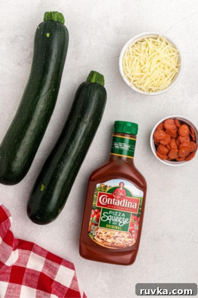 Quick & Easy Air Fryer Zucchini Pizza Boats 3 Zucchini, pizza sauce, cheese, and pepperoni on a white marble table.