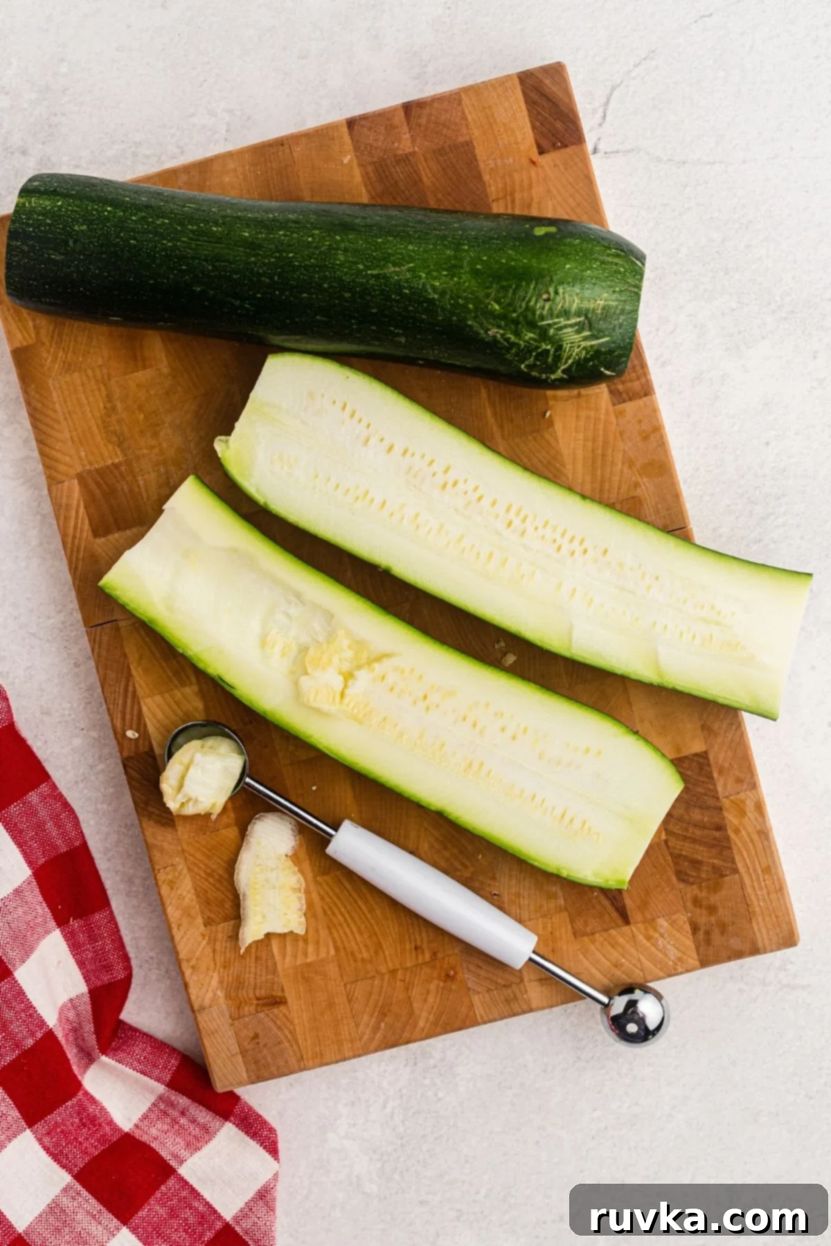 Quick & Easy Air Fryer Zucchini Pizza Boats 4 Zucchini sliced in half and then scooped out with melon baller on a cutting board