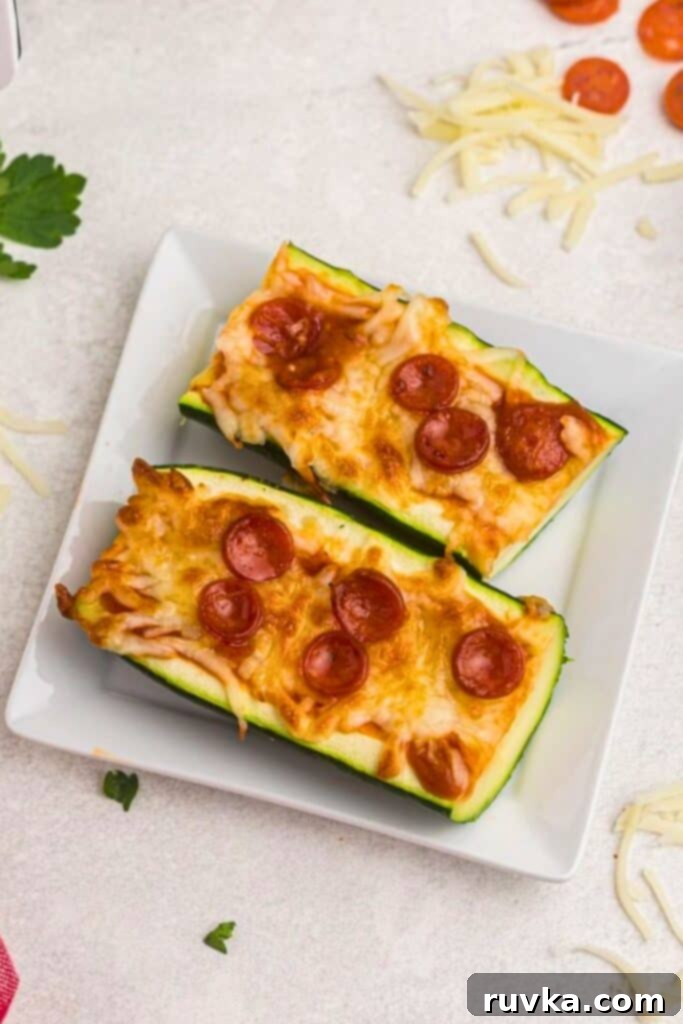 Quick & Easy Air Fryer Zucchini Pizza Boats 6 Zucchini boat pizza cut in half on a small white square plate.