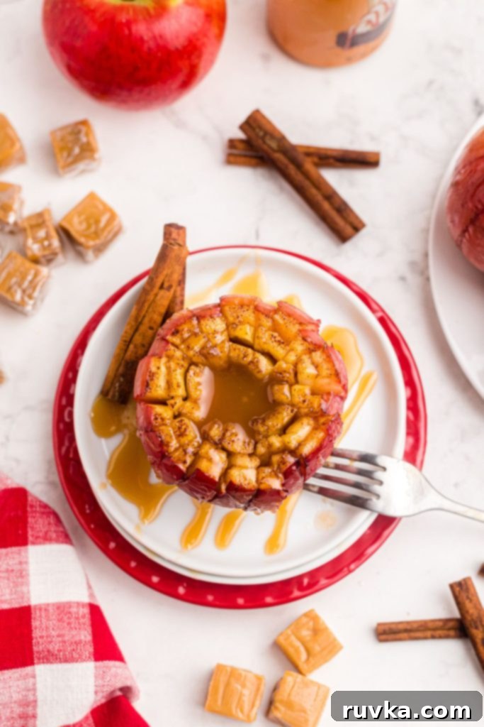 Air Fryer Blooming Apple Bliss 3 Beautifully sliced juicy apple filled with melted caramel, served on a white plate with a sprinkle of cinnamon and a fork beside it.