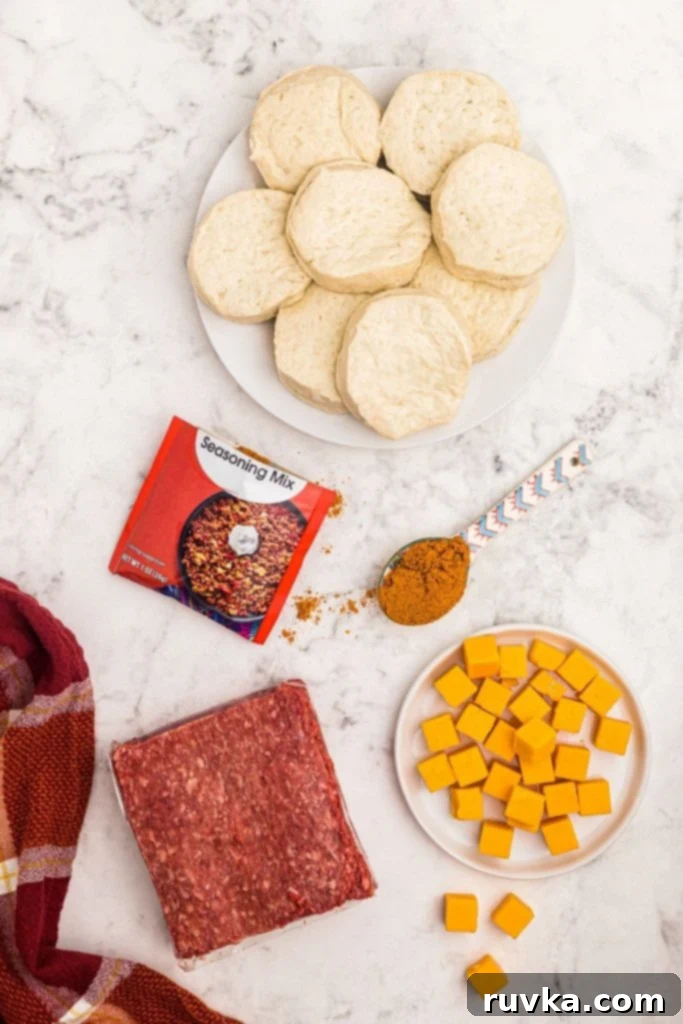 Crispy Air Fryer Taco Bombs 3 Ingredients needed to make taco bombs, meat, cheese cubes, and seasonings, with raw biscuit dough on a white marble table.
