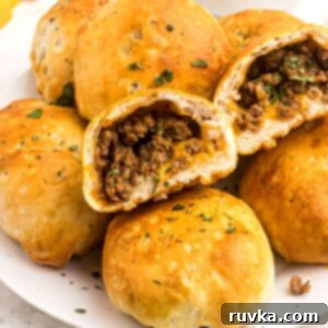 Crispy Air Fryer Taco Bombs 10 Golden biscuit dough filled with seasoned taco meat and cheddar cheese stacked on a white plate