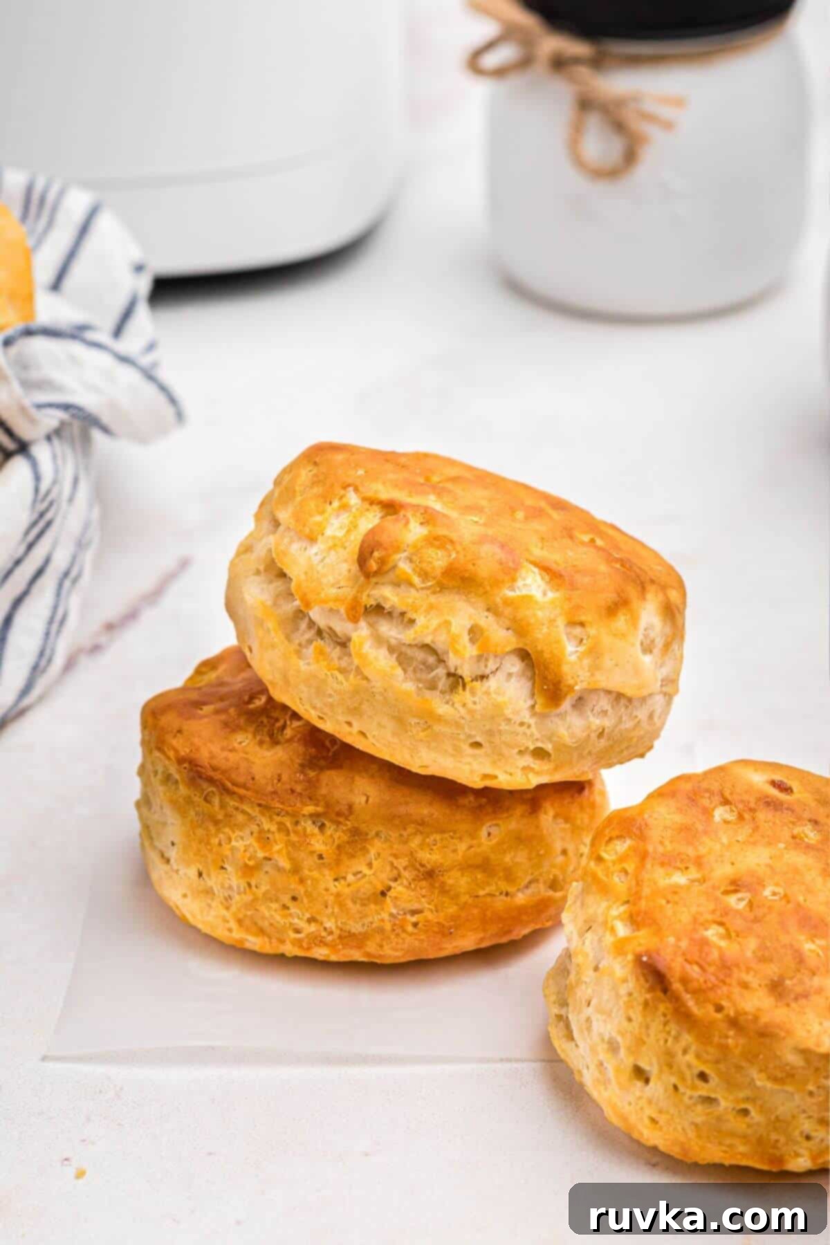 Fluffy Air Fryer Biscuits 2 Golden fluffy biscuits stacked in front of the air fryer.