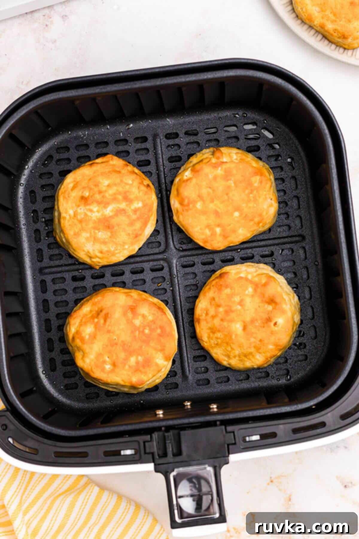 Fluffy Air Fryer Biscuits 5 Golden biscuits in the air fryer basket after being air fried.