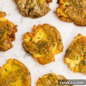 Air Fryer Crispy Smashed Potatoes 9 Golden crispy smashed potatoes on a white marble table garnished with parsley flakes