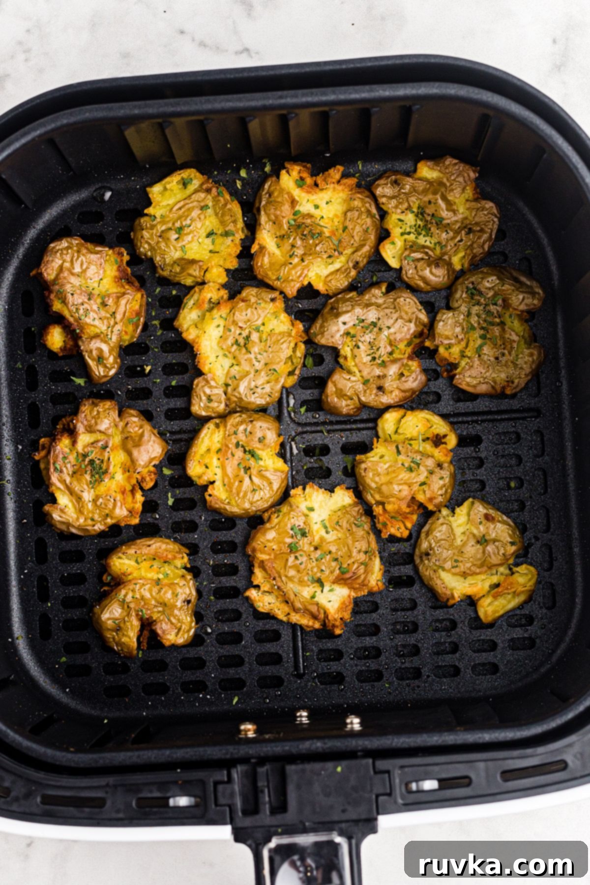 Air Fryer Crispy Smashed Potatoes 7 Golden crispy smashed potatoes in the air fryer basket after being perfectly cooked, ready to serve.