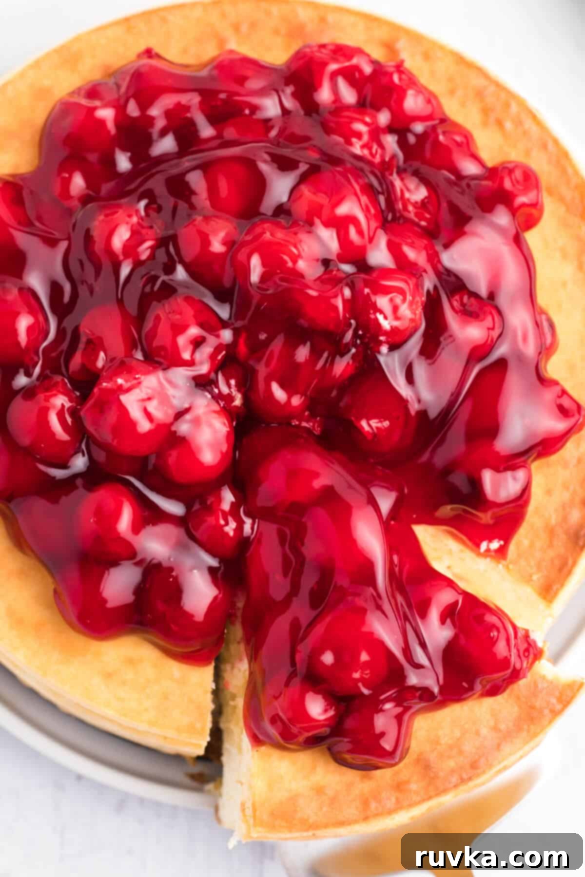 Perfect Air Fryer Cheesecake 3 An overhead shot captures a perfectly baked air fryer cheesecake, being effortlessly sliced into generous portions, ready for serving.