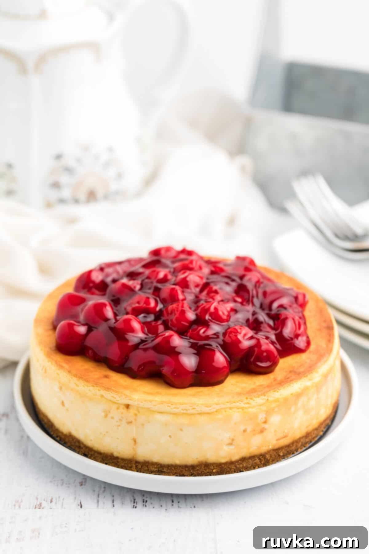 Perfect Air Fryer Cheesecake 8 A vibrant air fryer cheesecake, adorned with a glossy cherry topping, is beautifully presented on a white plate, ready to be enjoyed.